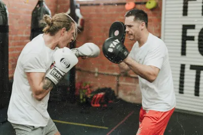 Entrenador de boxeo y cliente haciendo ejercicio con guantes